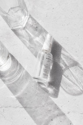 A close-up of mounjaslim spray bottle next to fresh fruits and a glass of water on a kitchen counter.
