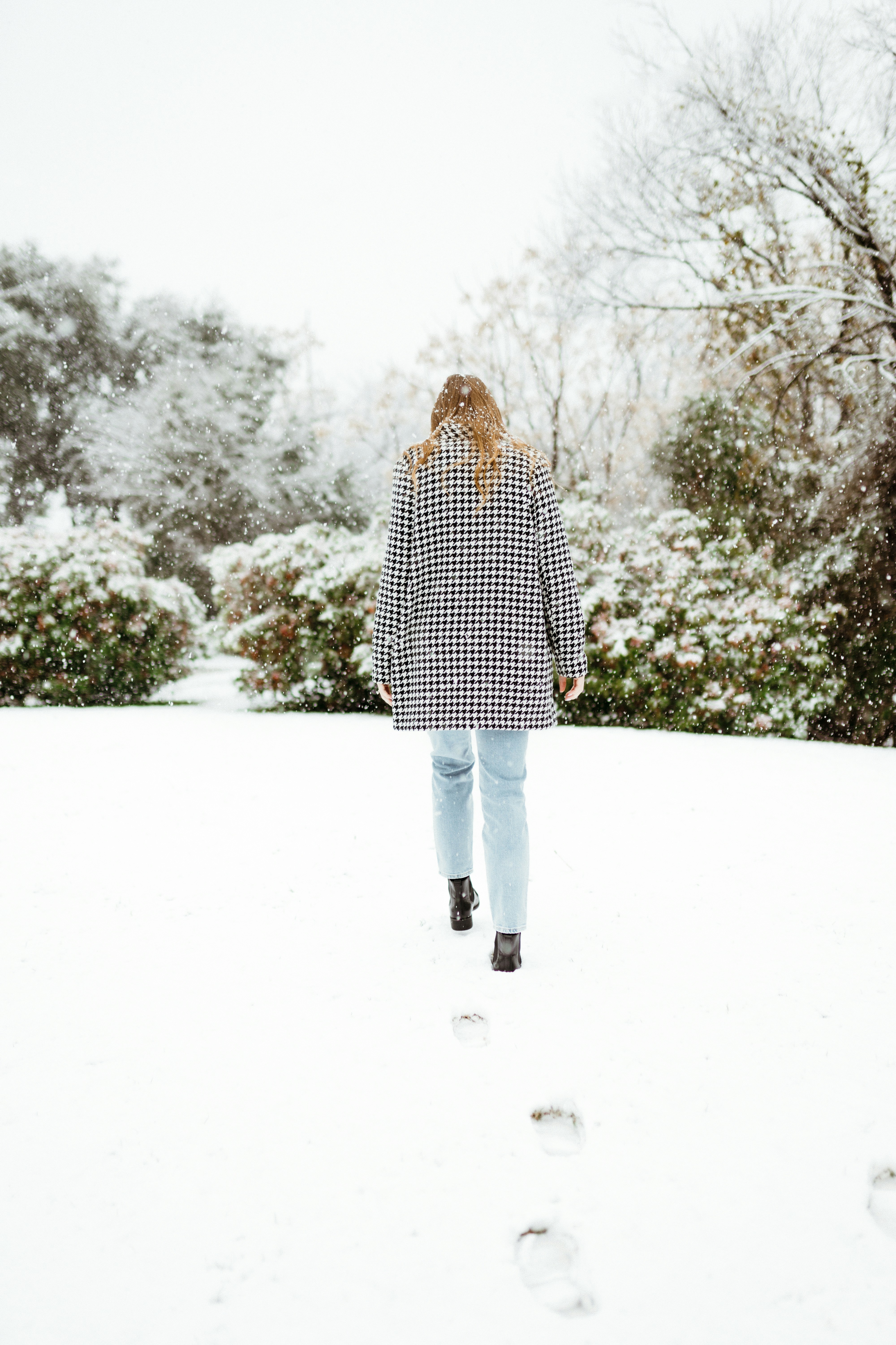 woman in black and white polka dot coat standing on snow covered ground during daytime