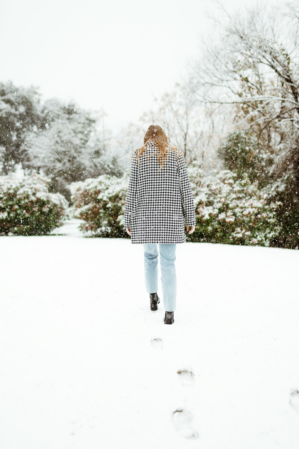 woman in black and white polka dot coat standing on snow covered ground during daytime