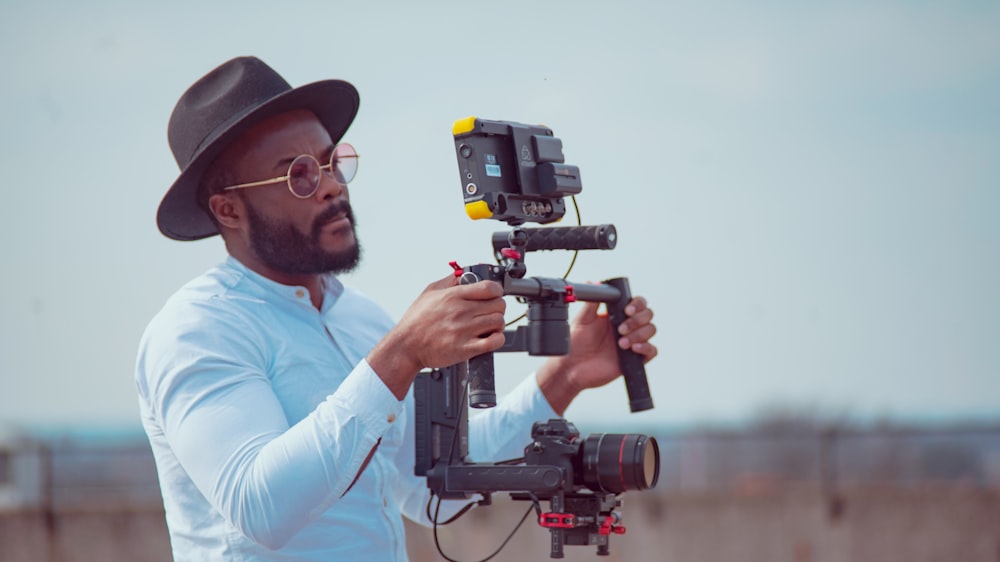 man in white dress shirt holding black video camera