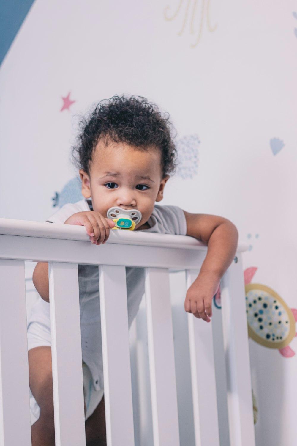 baby in white crib with pacifier