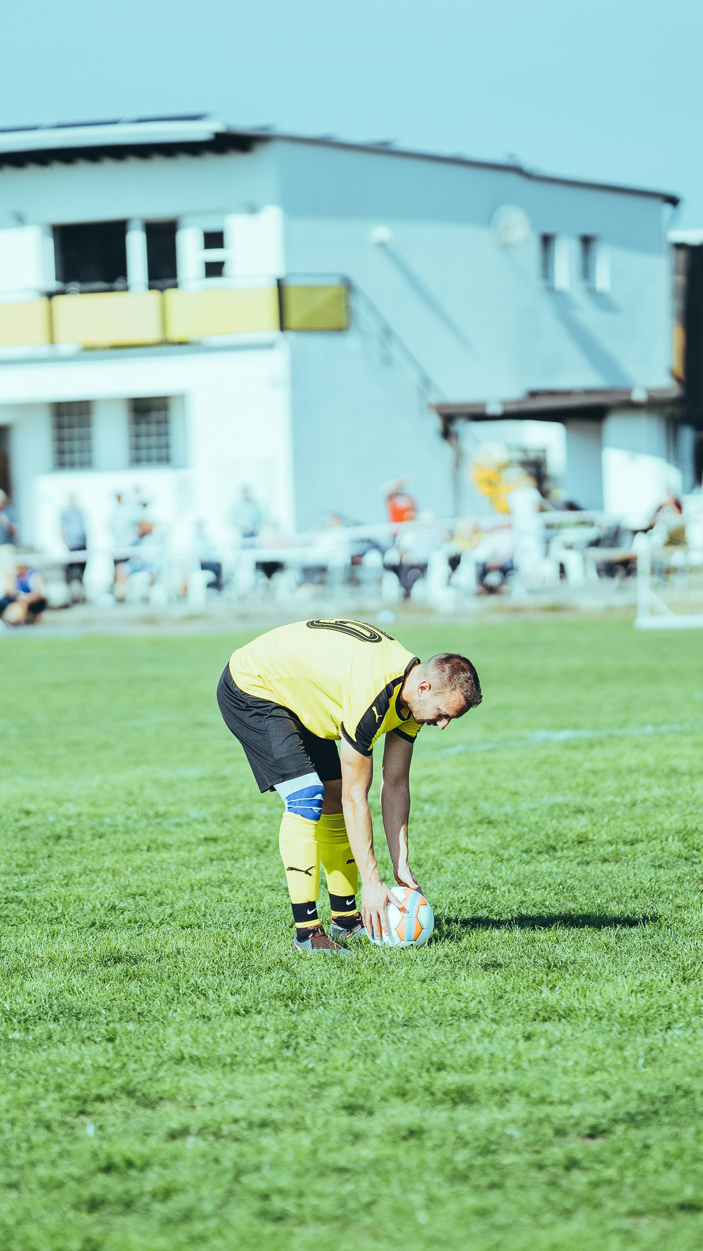 man in yellow shirt and black shorts playing soccer during daytime