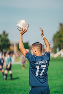 man in blue and white adidas soccer jersey shirt holding white and blue soccer ball