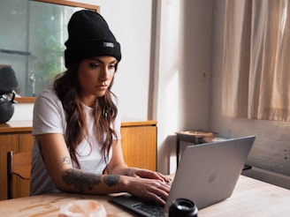 woman in black knit cap using macbook onlyfans