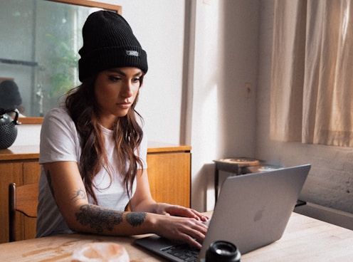 woman in black knit cap using macbook onlyfans