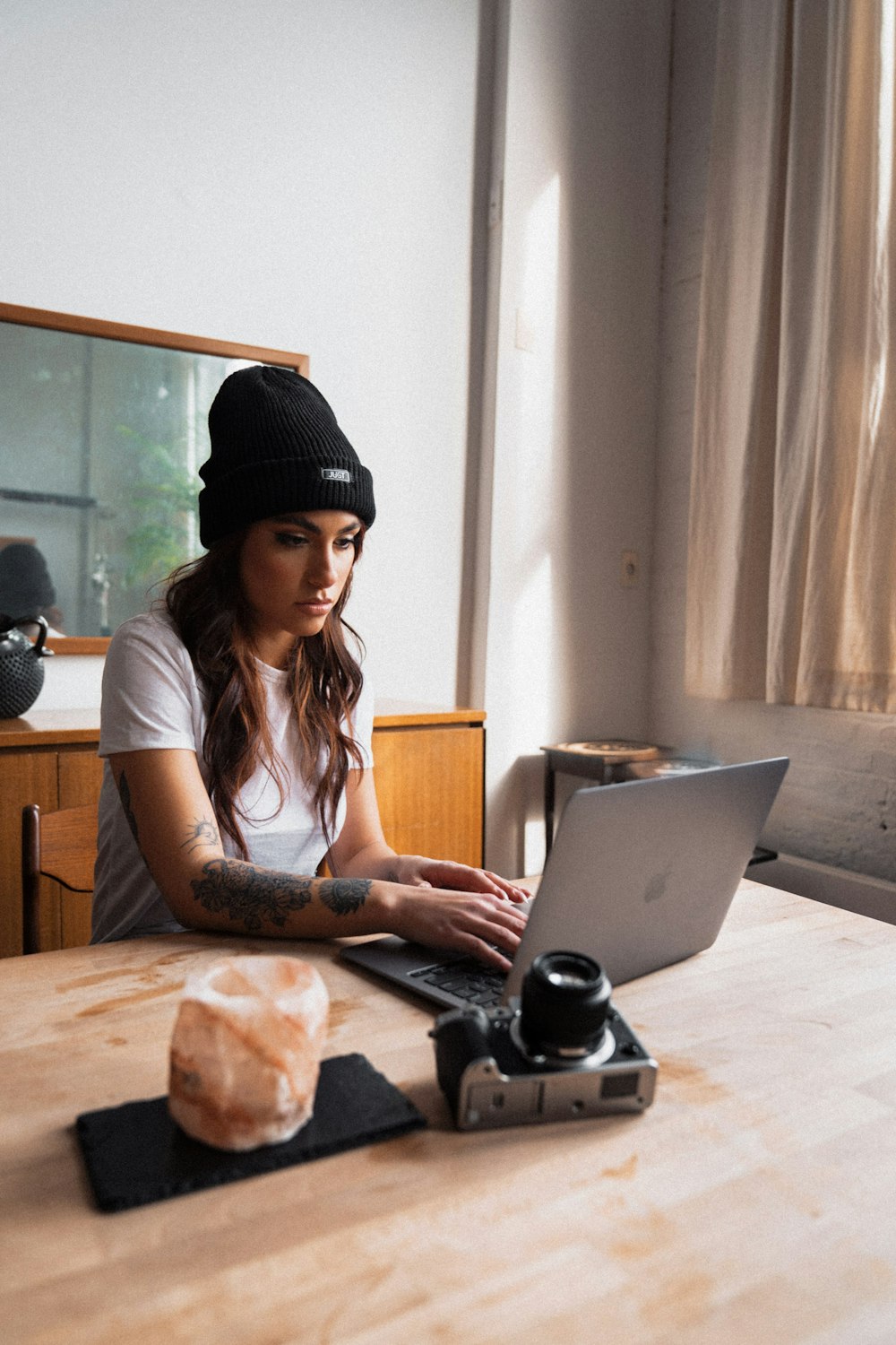 Frau in schwarzer Strickmütze mit MacBook