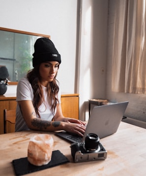 woman in black knit cap using macbook