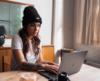 woman in black knit cap using macbook