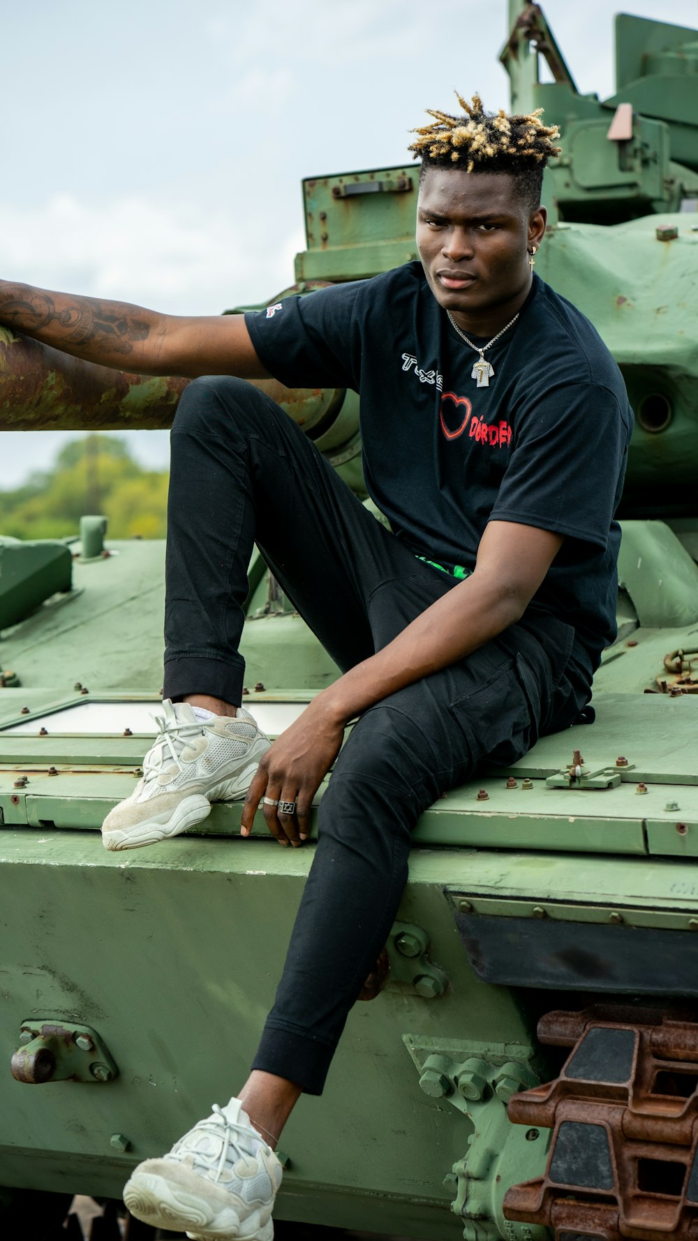 man in black crew neck t-shirt and blue denim jeans sitting on green wooden bench