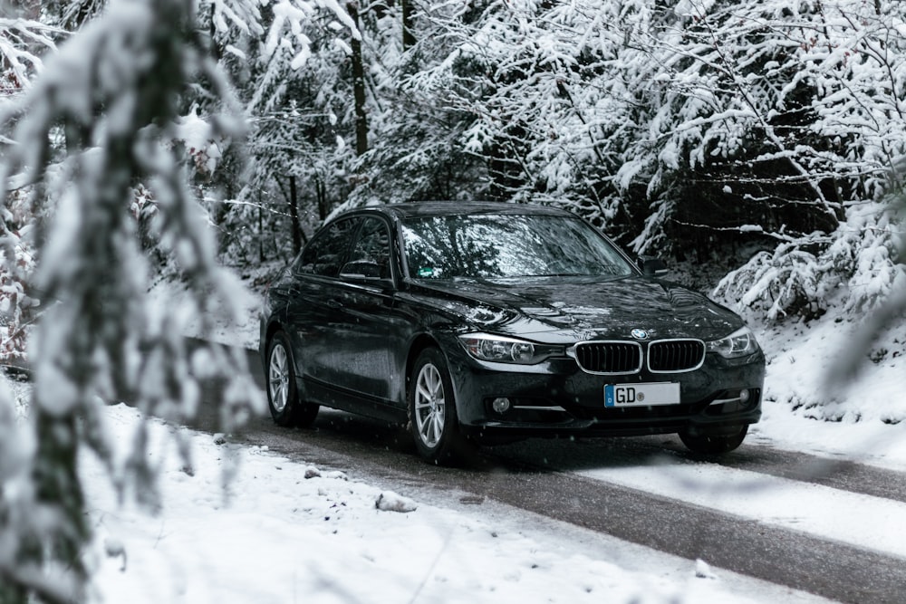 BMW Sedán negro en carretera cubierta de nieve durante el día