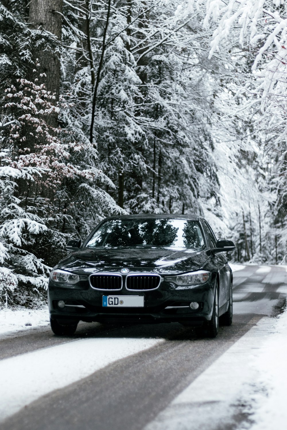 black bmw car on road covered with snow