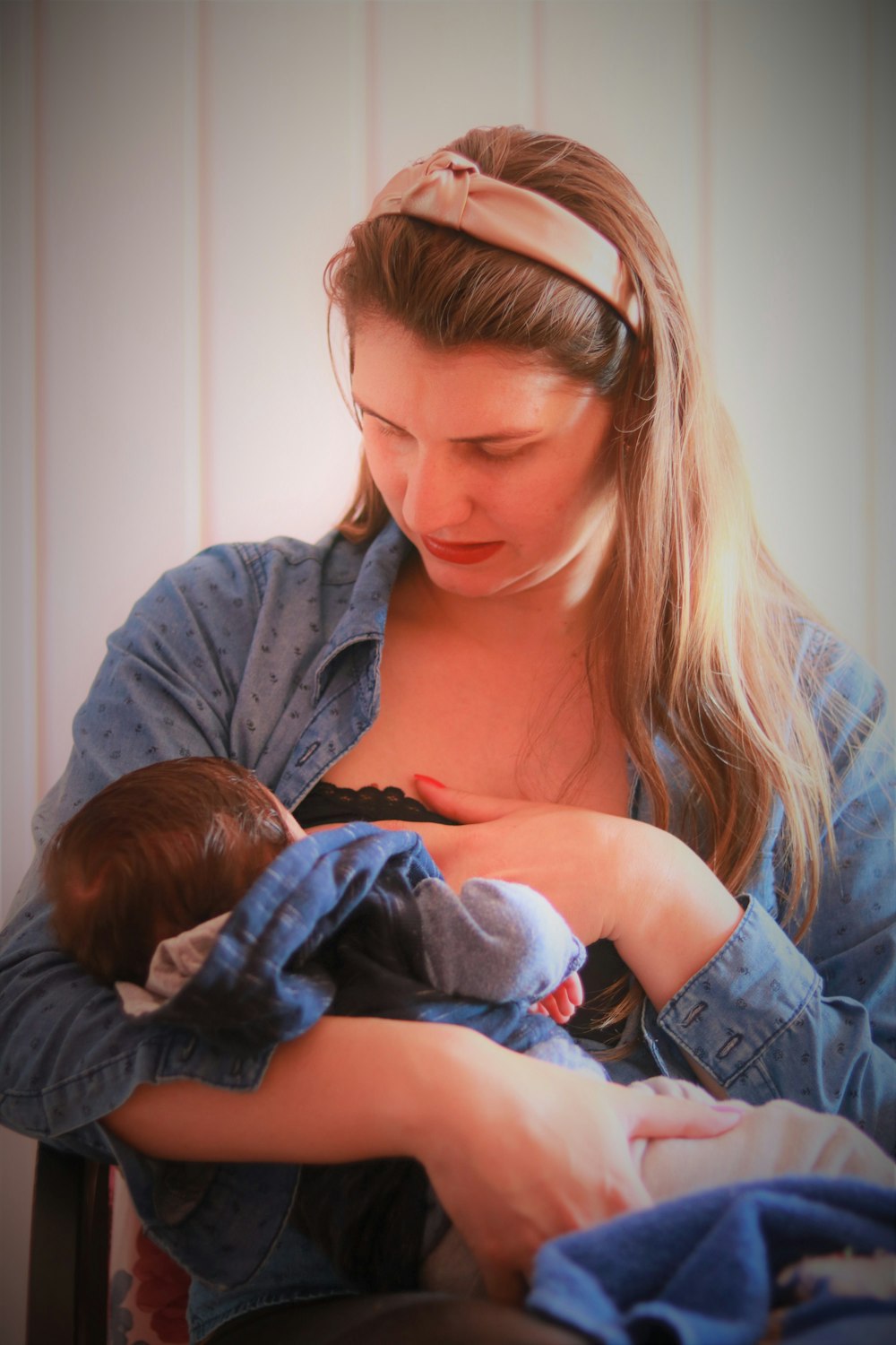 woman in blue denim jacket carrying baby