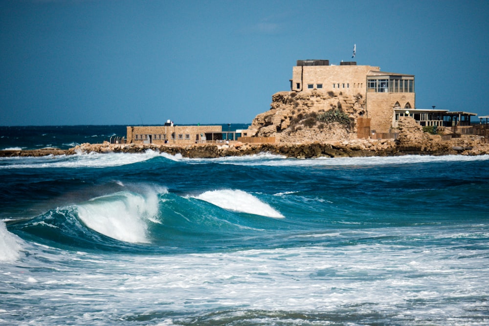 brown concrete building on white and blue ocean water during daytime