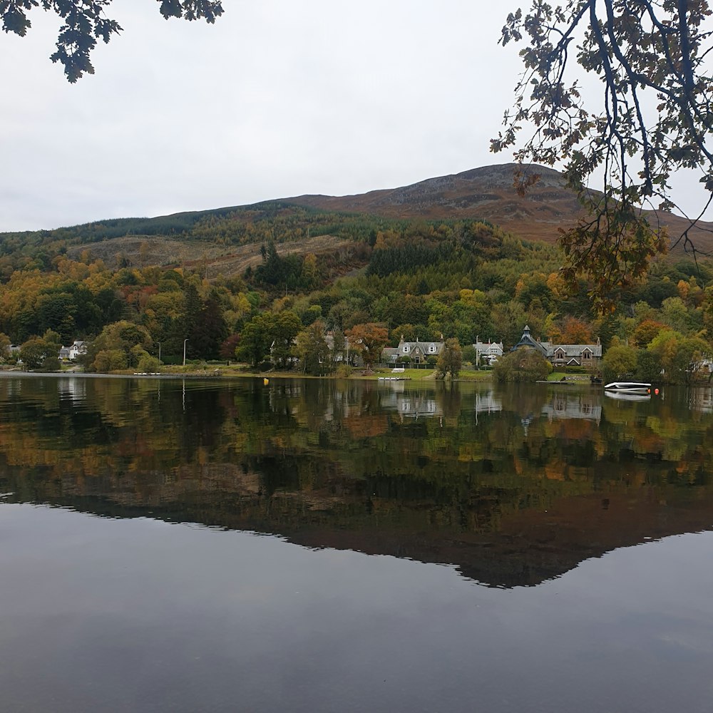 green and brown mountain beside lake under white cloudy sky during daytime