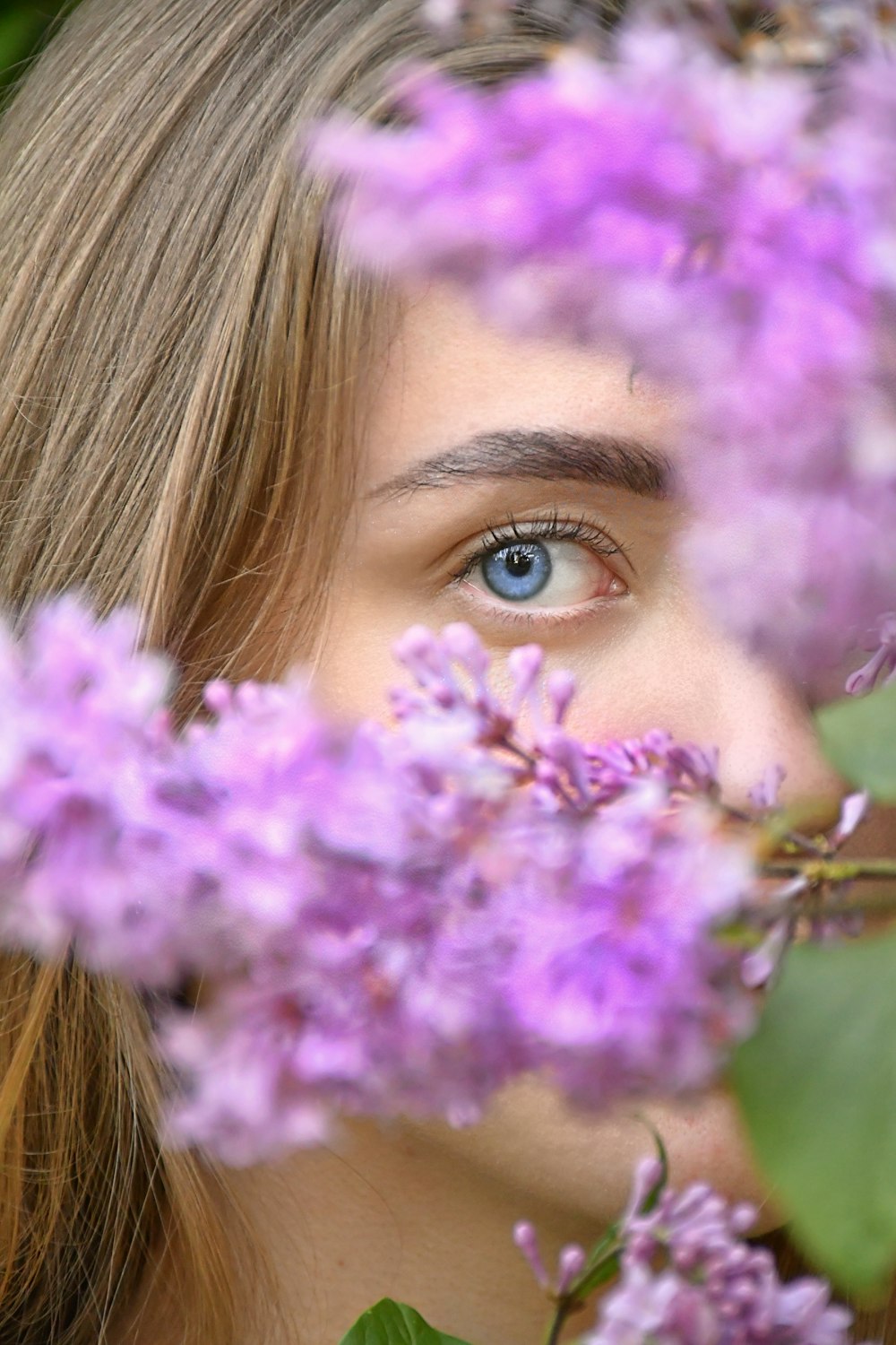 Frau mit blonden Haaren hält lila Blume