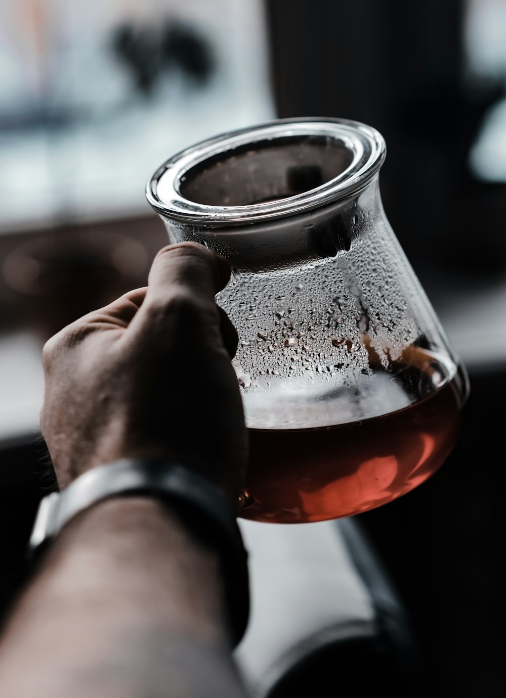 person holding clear glass jar with red liquid