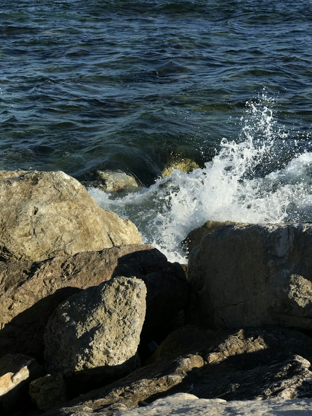 brown rocky shore with sea waves crashing on rocks