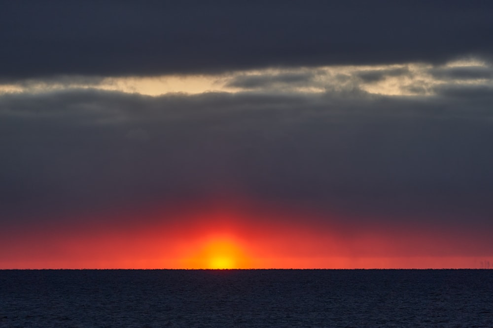 body of water under cloudy sky during sunset