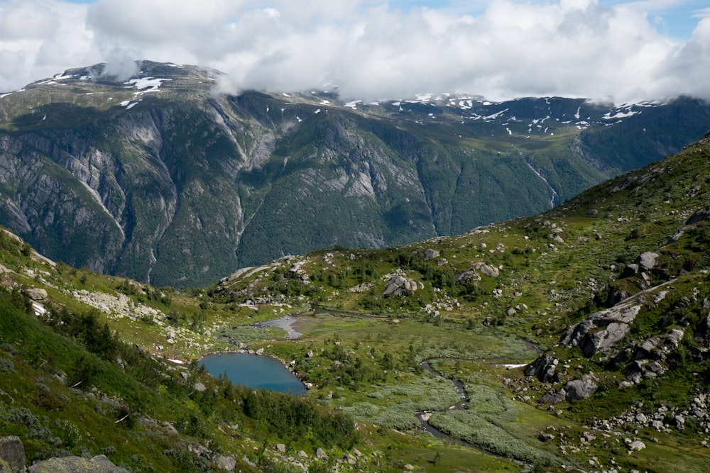 green grass field and mountains under white clouds during daytime