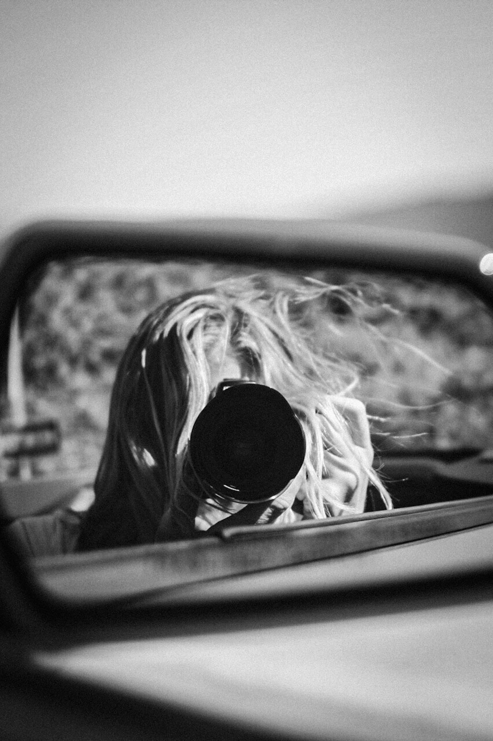 woman taking photo of car side mirror