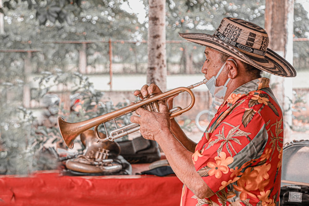 Hombre con camisa floral roja y blanca tocando la trompeta