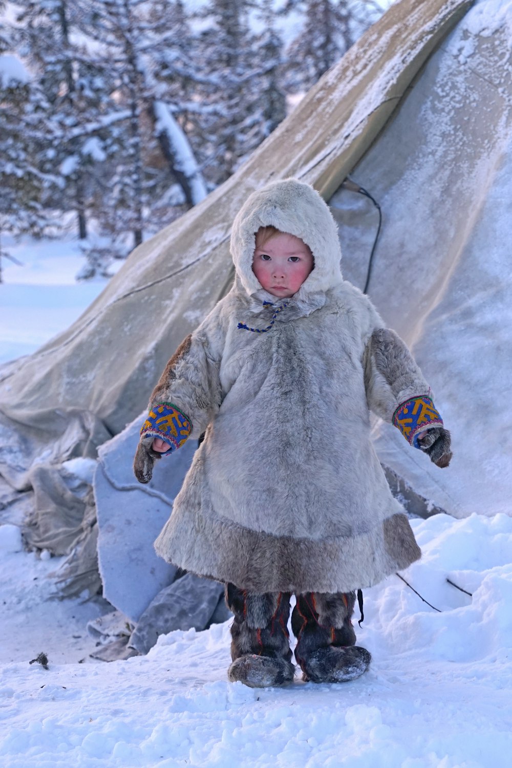 Muchacha con abrigo gris de pie en el suelo cubierto de nieve durante el día