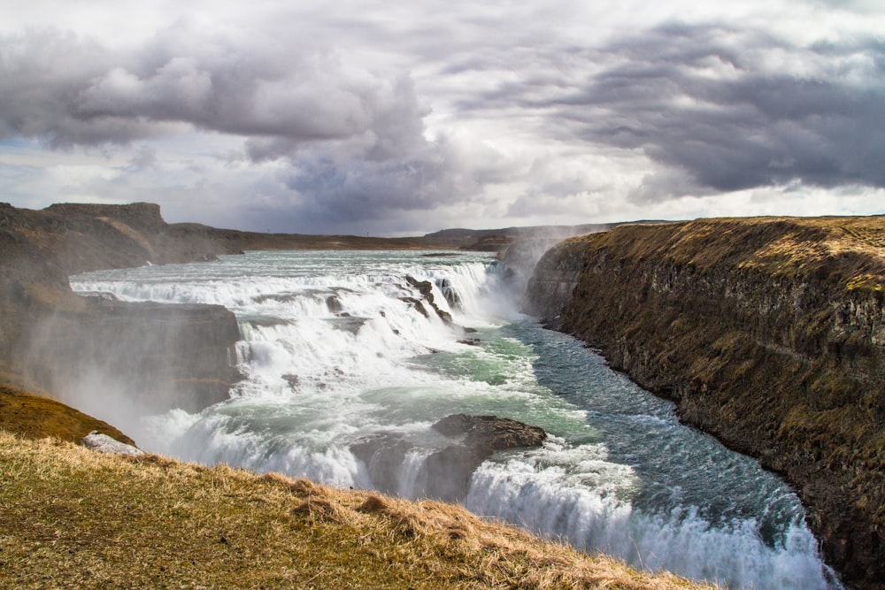 water falls under cloudy sky during daytime