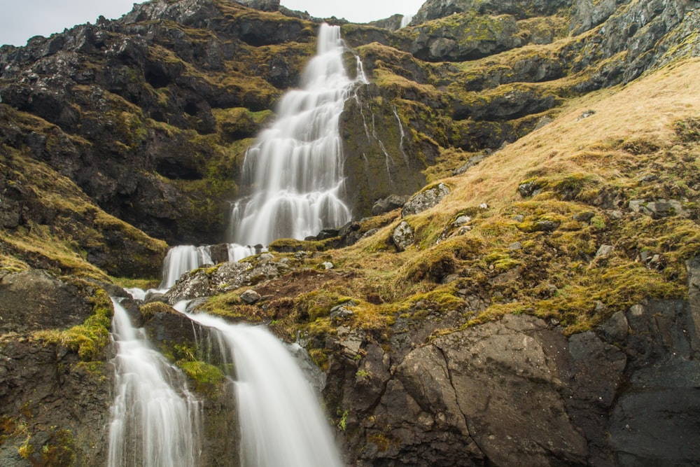 waterfalls on brown rocky mountain during daytime