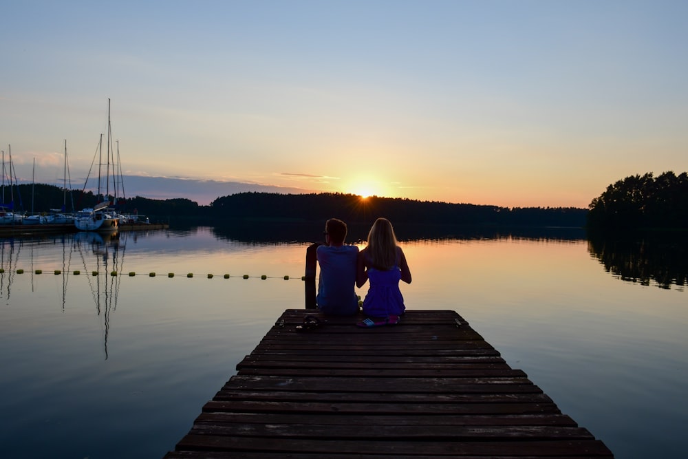 couple sitting on dock during sunset