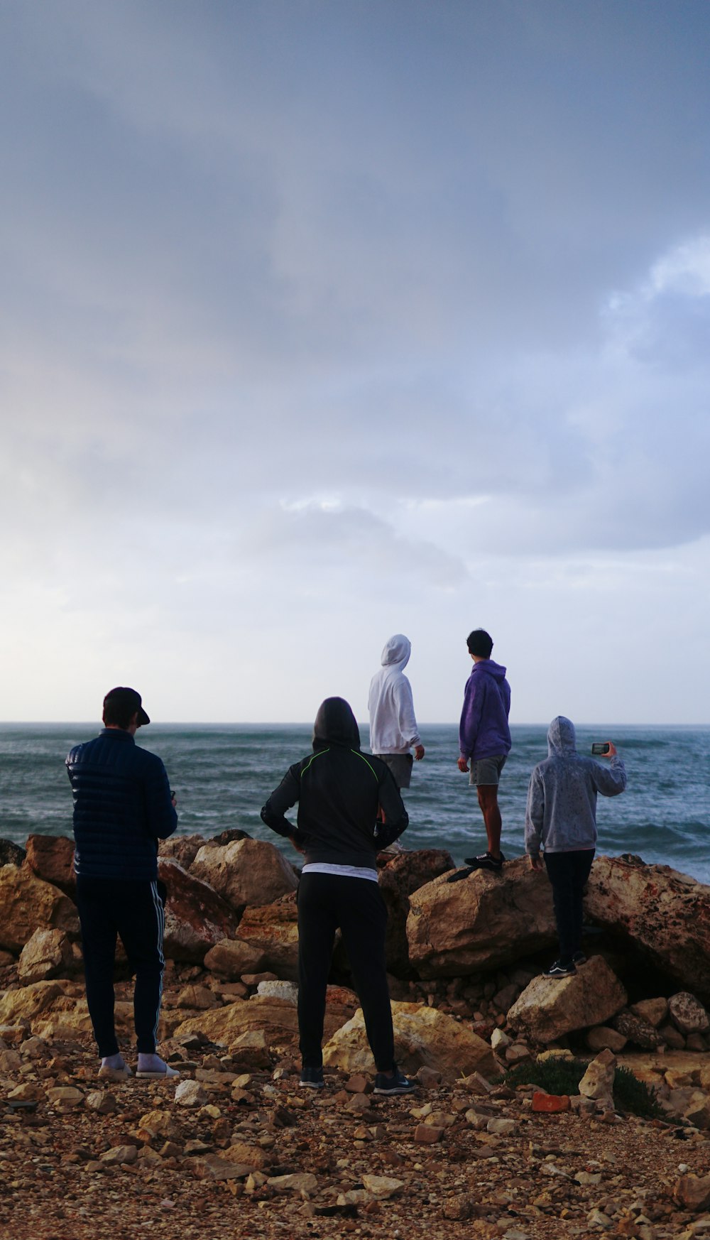 man and woman standing on rock near body of water during daytime