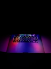 A sleek refurbished laptop glowing softly under blue and violet galaxy-themed lighting.