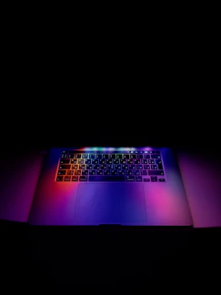 A sleek laptop with a glowing blue keyboard on a modern desk.
