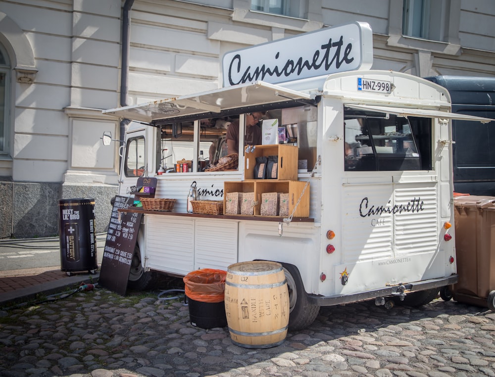 white and black food truck parked near white concrete building during daytime