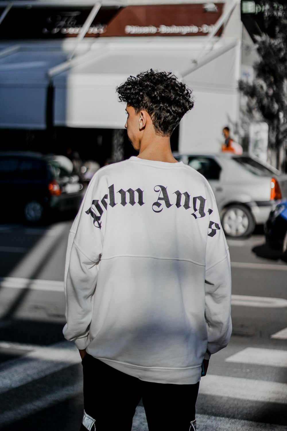 man in white and black sweater standing on sidewalk during daytime