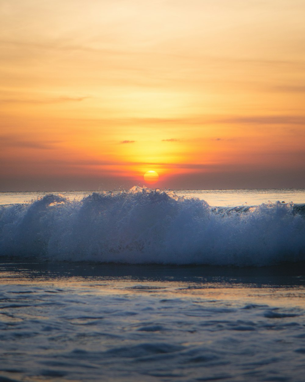 sea waves crashing on shore during sunset