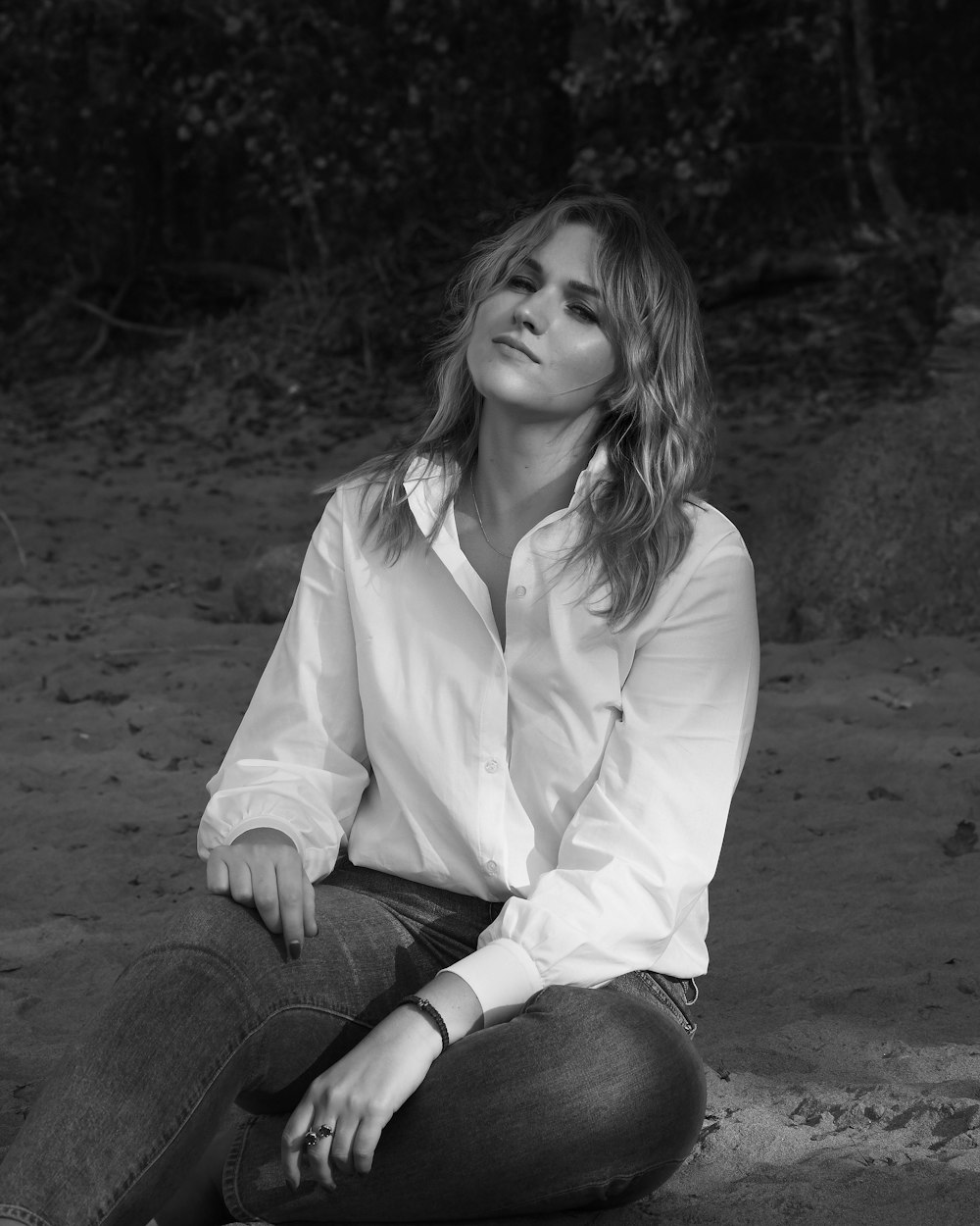 woman in white dress shirt and black denim jeans sitting on ground