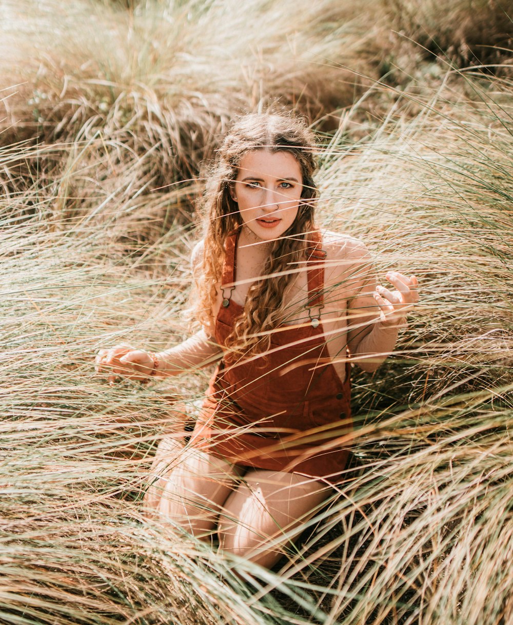 woman in brown long sleeve mini dress sitting on brown grass during daytime