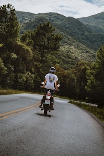 man in white t-shirt riding bicycle on road during daytime