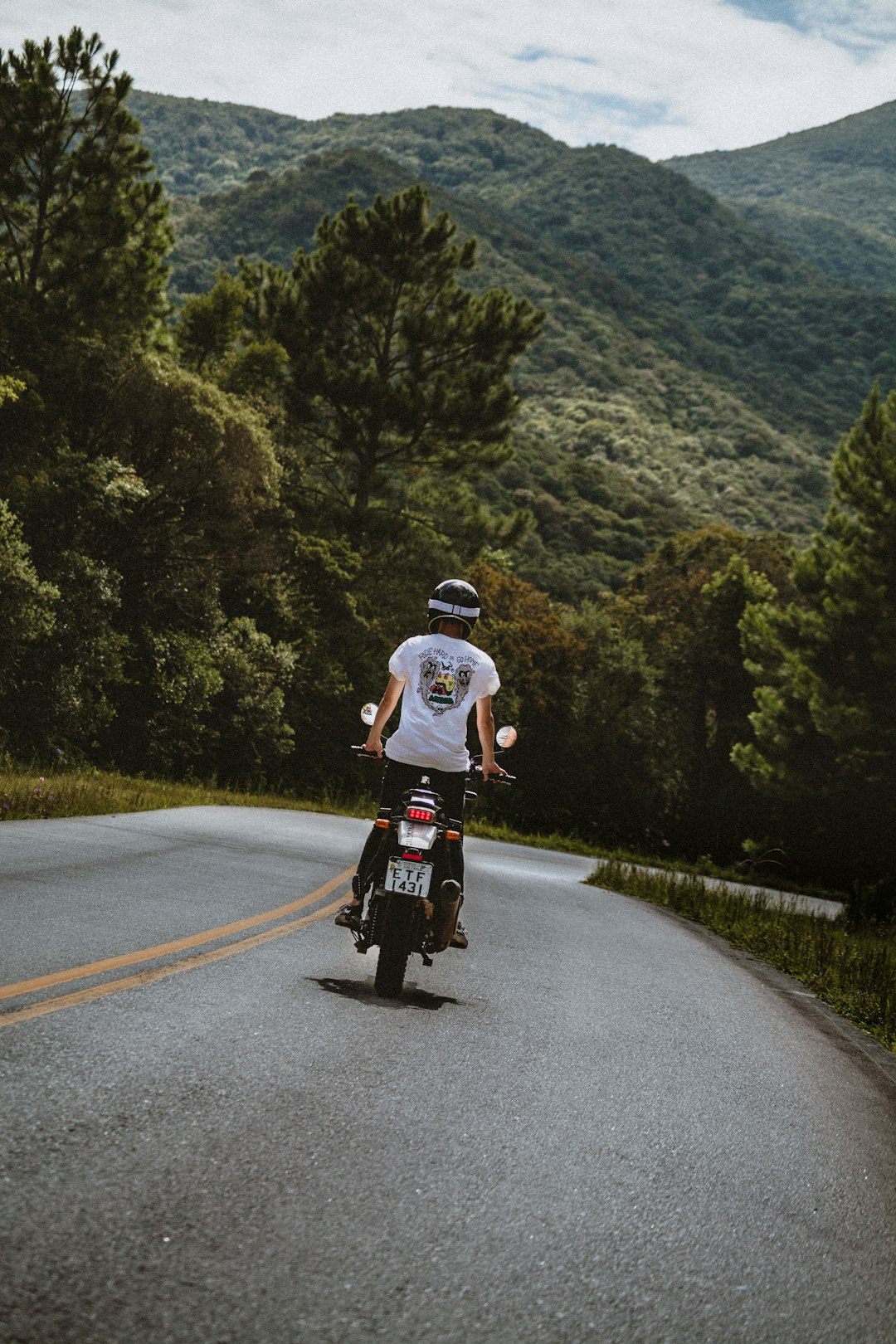 man in white t-shirt riding bicycle on road during daytime