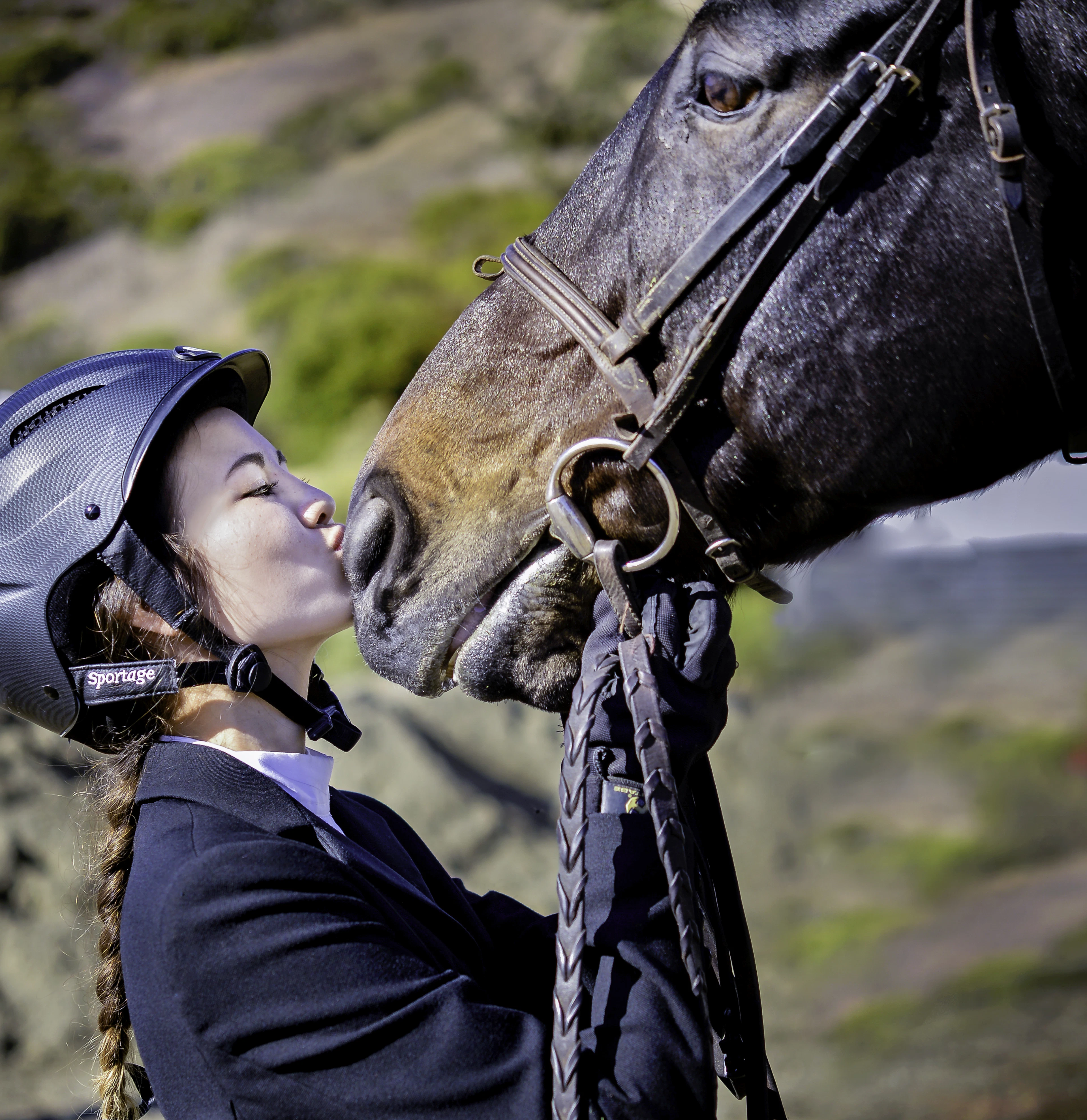 Jinete con casco de equitación besando a su caballo