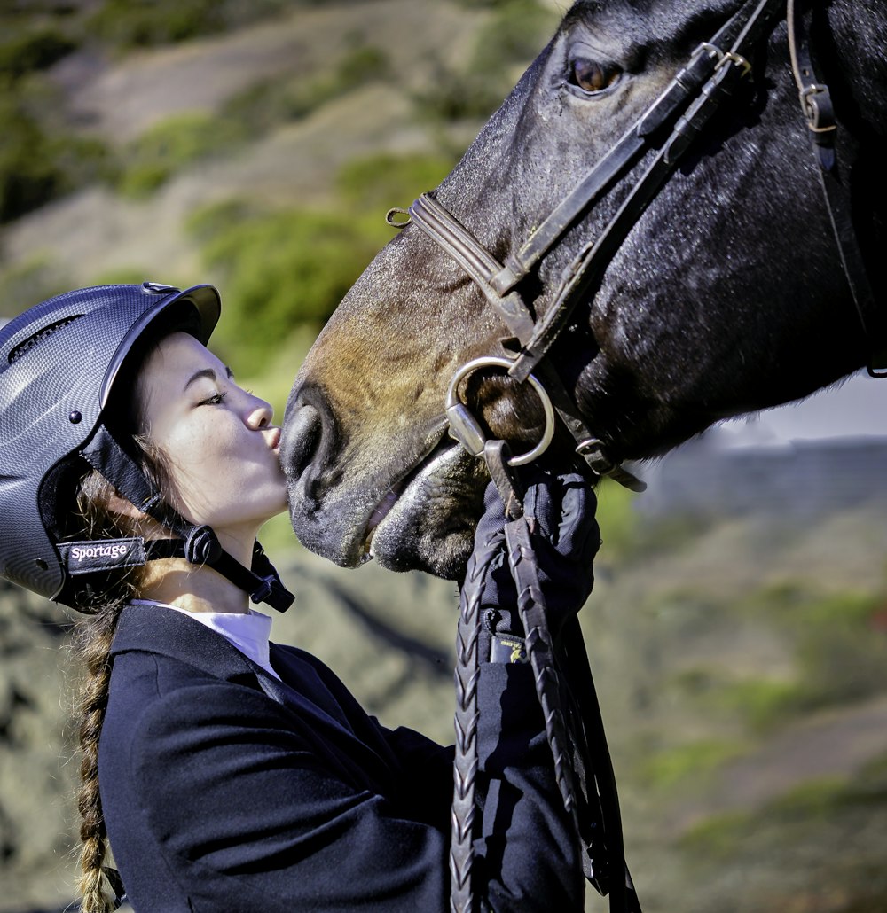 man in black jacket wearing black helmet riding brown horse during daytime