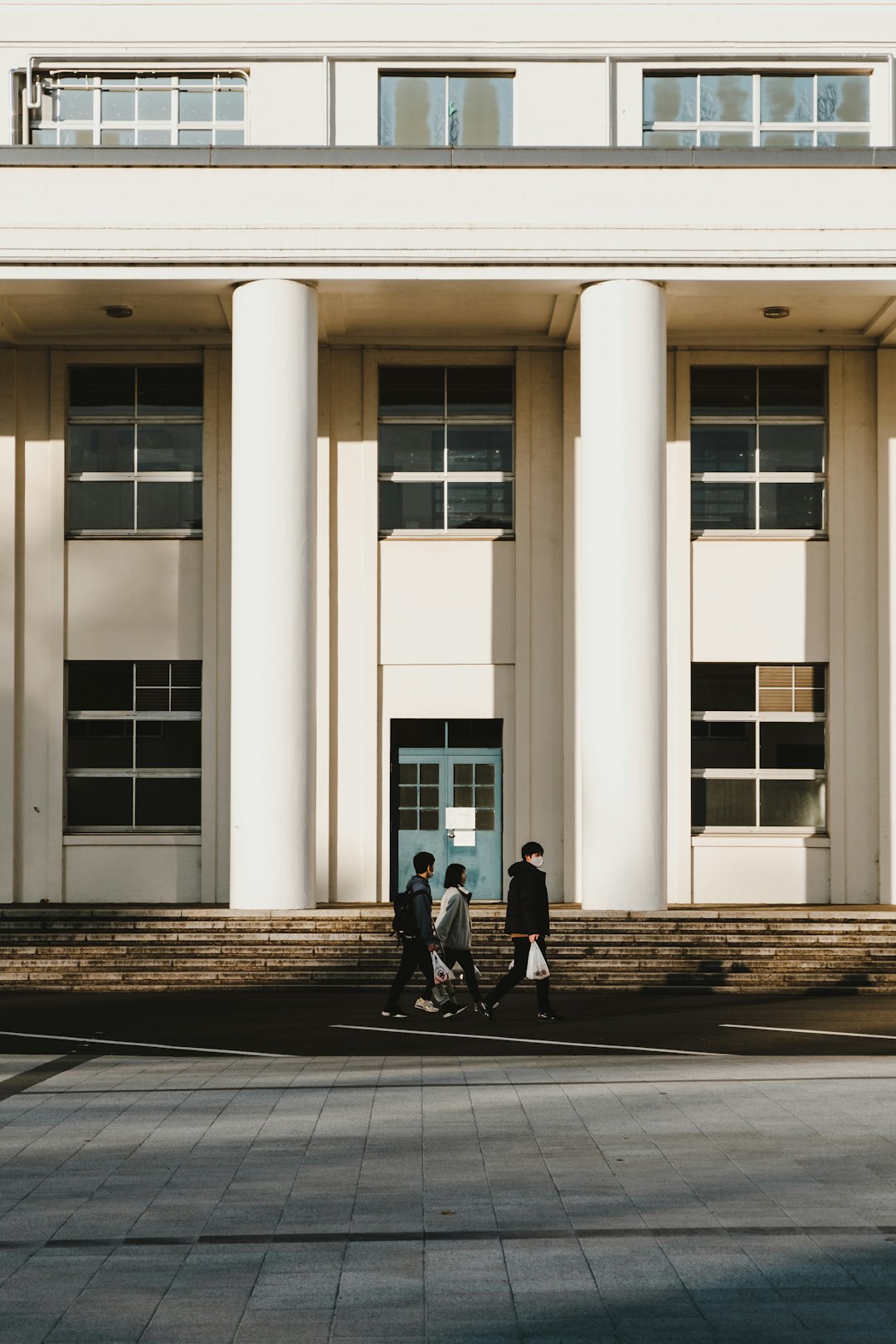 2 person walking on sidewalk near white building during daytime