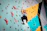 A climber reaching the top of a challenging indoor climbing wall, smiling with satisfaction.