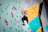 A focused climber gripping a colorful hold on a steep indoor wall inside picoviva gym.