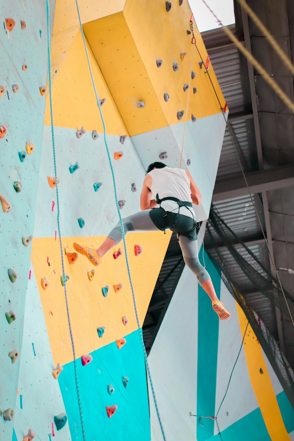 woman in white t-shirt and blue denim jeans jumping on multi colored wall