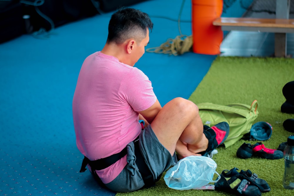 boy in pink t-shirt and black shorts sitting on green textile