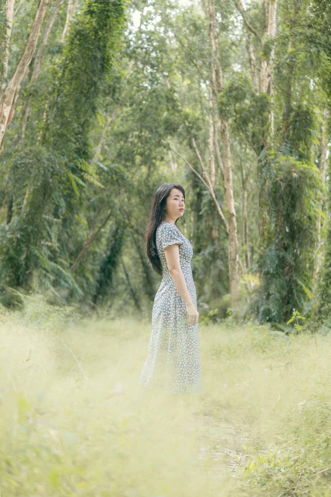 woman in white and black dress standing on green grass field surrounded by green trees during