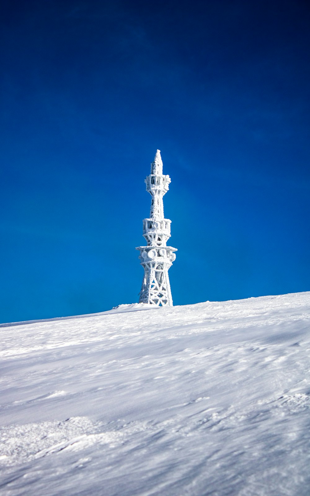 white tower on snow covered ground under blue sky during daytime