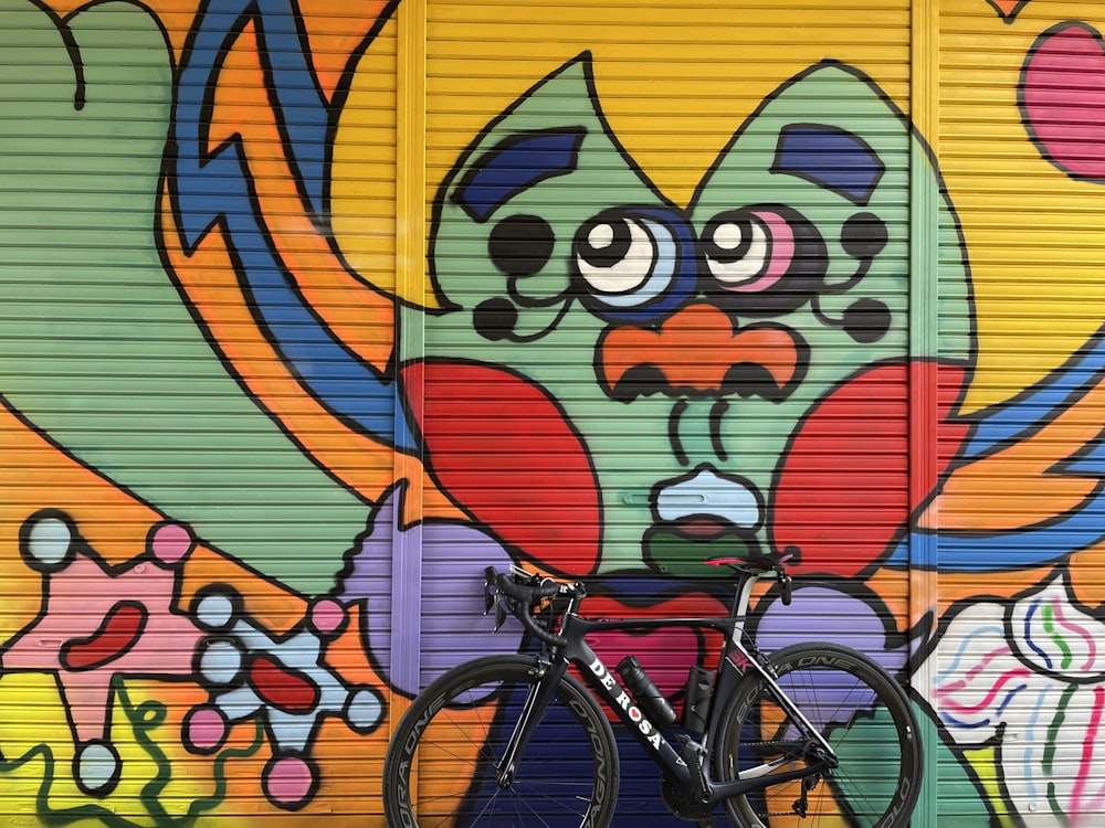 black bicycle with red and yellow heart wall graffiti
