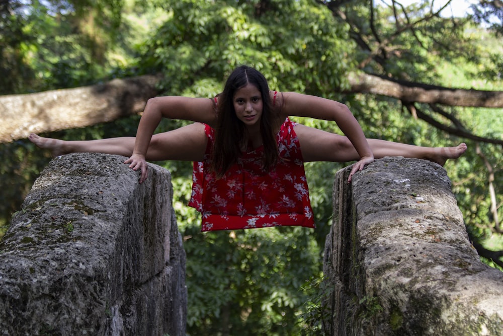 woman in red dress sitting on brown tree trunk